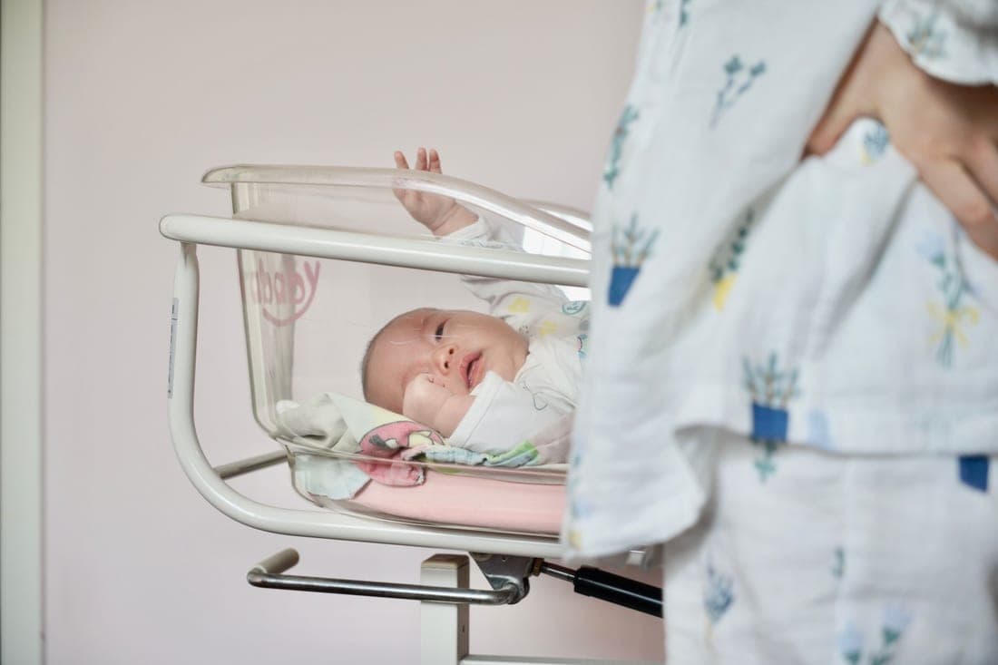 A newborn lying flat in a stroller bassinet
