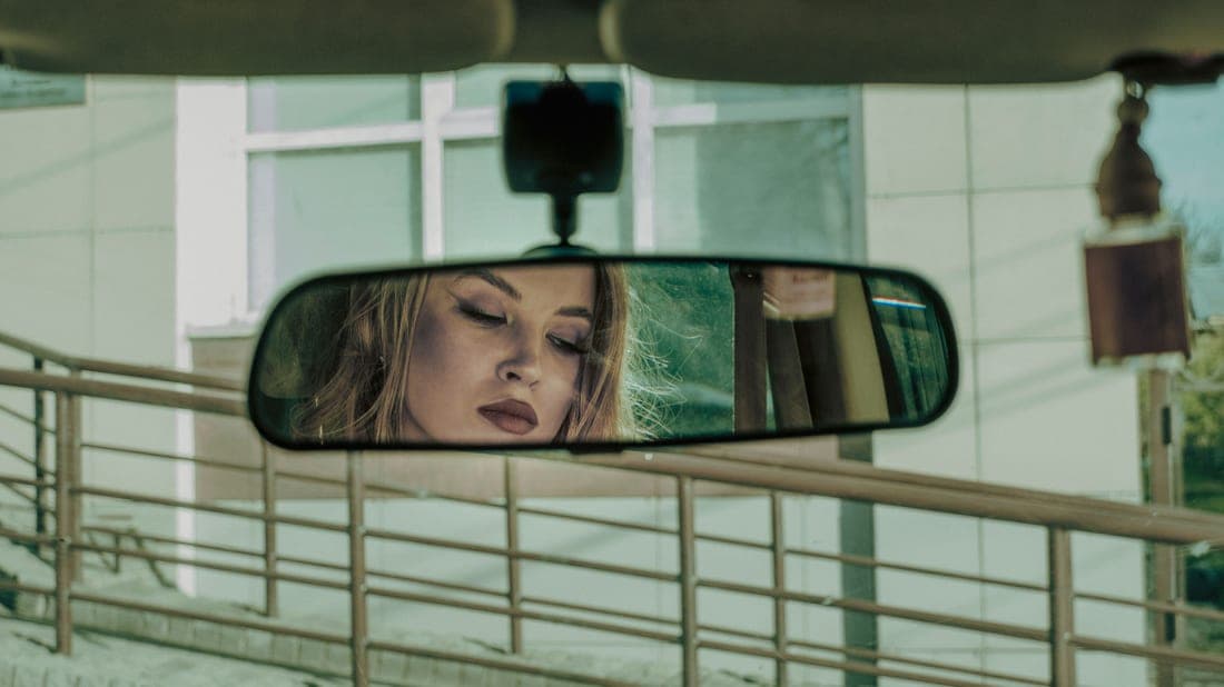 A mirror mounted on a rear headrest showing the back seat