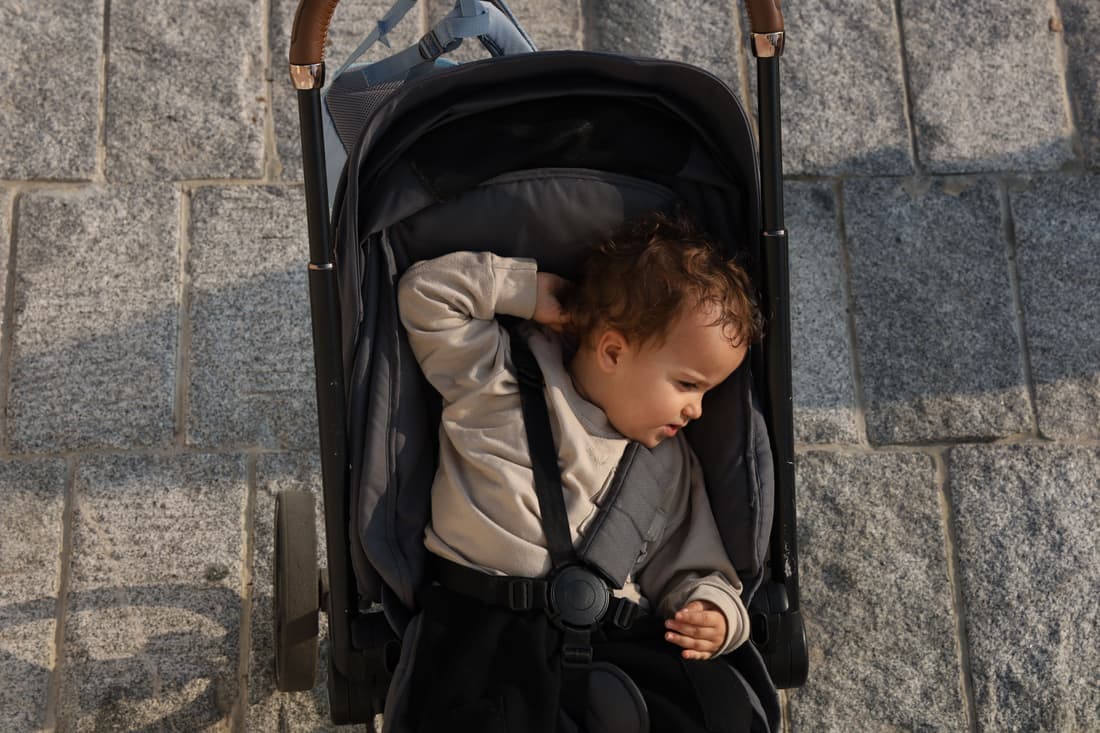 A toddler sitting in a lightweight umbrella stroller