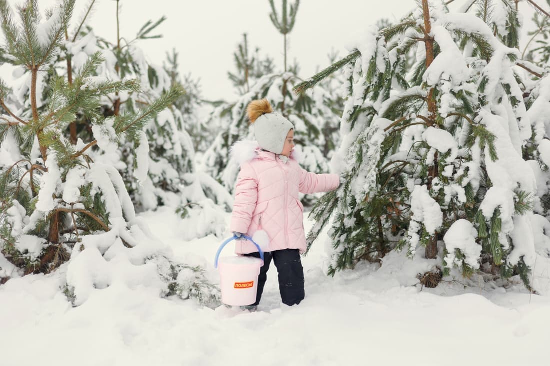 A child in a winter coat beside a car seat